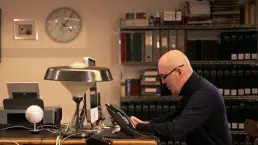 Thumbnail cuadrado de la producción del mini documental de Fedeli, mostrando al protagonista en su escritorio trabajando con el teléfono, producido por LUP Studio.