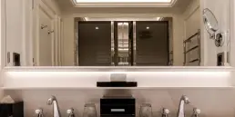 Fotografía de interiores profesional mostrando la simetría del lavabo doble en una suite del Hotel Sofitel Barcelona, con iluminación cálida integrada.