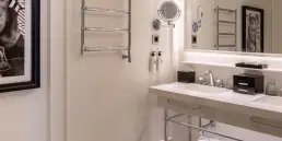 Fotografía de interiores profesional del baño de una suite en el Hotel Sofitel Barcelona, destacando la decoración con cuadros artísticos, lavabo doble y acabados de lujo.