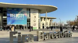 Vista vertical de la fachada de Fira Barcelona durante el MWC 2023, destacando el letrero de Fira Barcelona en primer plano y la publicidad del evento. Fotografía optimizada para dispositivos móviles por LUP Studio.