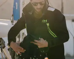 Persona vistiendo una chaqueta técnica de navegación de la marca NTN Ocean Wear, ajustando el equipo a bordo de un barco, con enfoque en los detalles de diseño y la calidad del material.