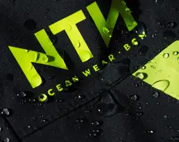 Detalle de gotas de agua sobre el tejido técnico de una prenda NTN Ocean Wear, destacando la calidad del contenido digital ecommerce producido por LUP Studio.