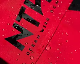 Primer plano de gotas de agua sobre el tejido rojo de una prenda NTN Ocean Wear, ejemplo de contenido digital ecommerce realizado por LUP Studio.